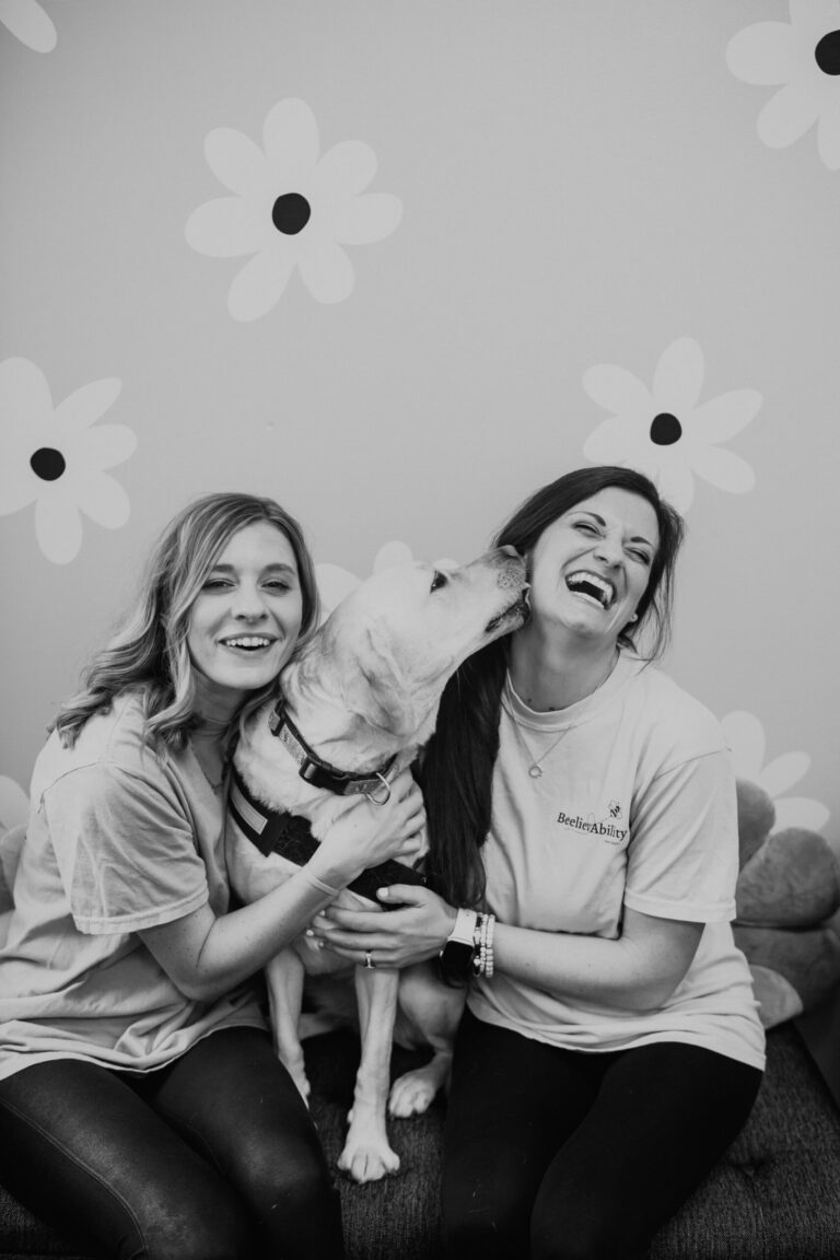 portrait of two young ladies with a dog in an indoor setting