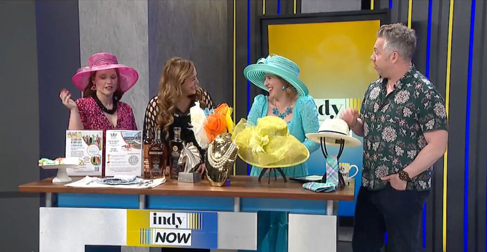 Ladies in Debry hats stand along side a gentleman for Indy Now as they present the Celebration of Hope Gala